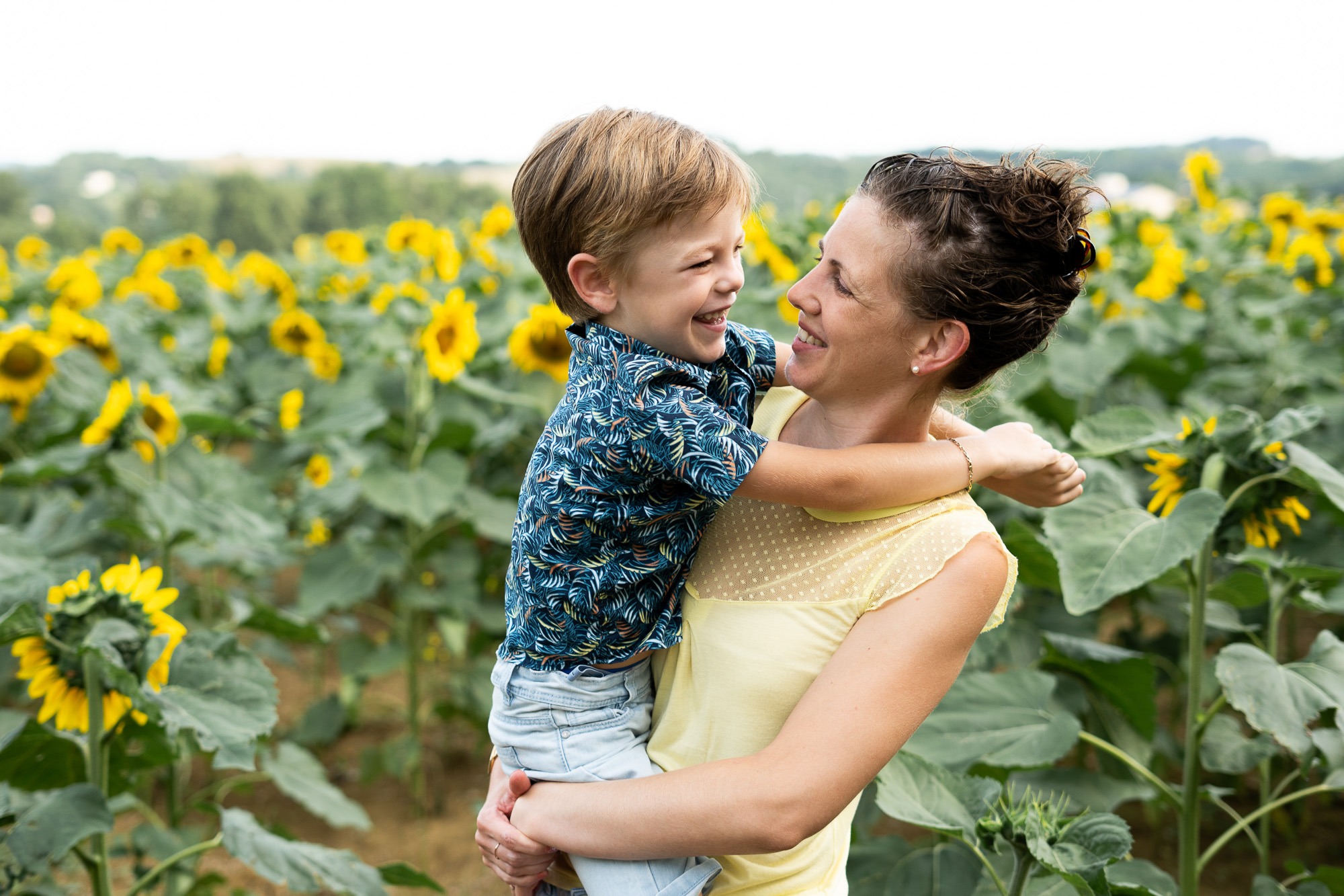 petit garçon heureux s'amuse avec sa maman au milieu des tournesols lors d'un shooting photo en extérieur à Castres